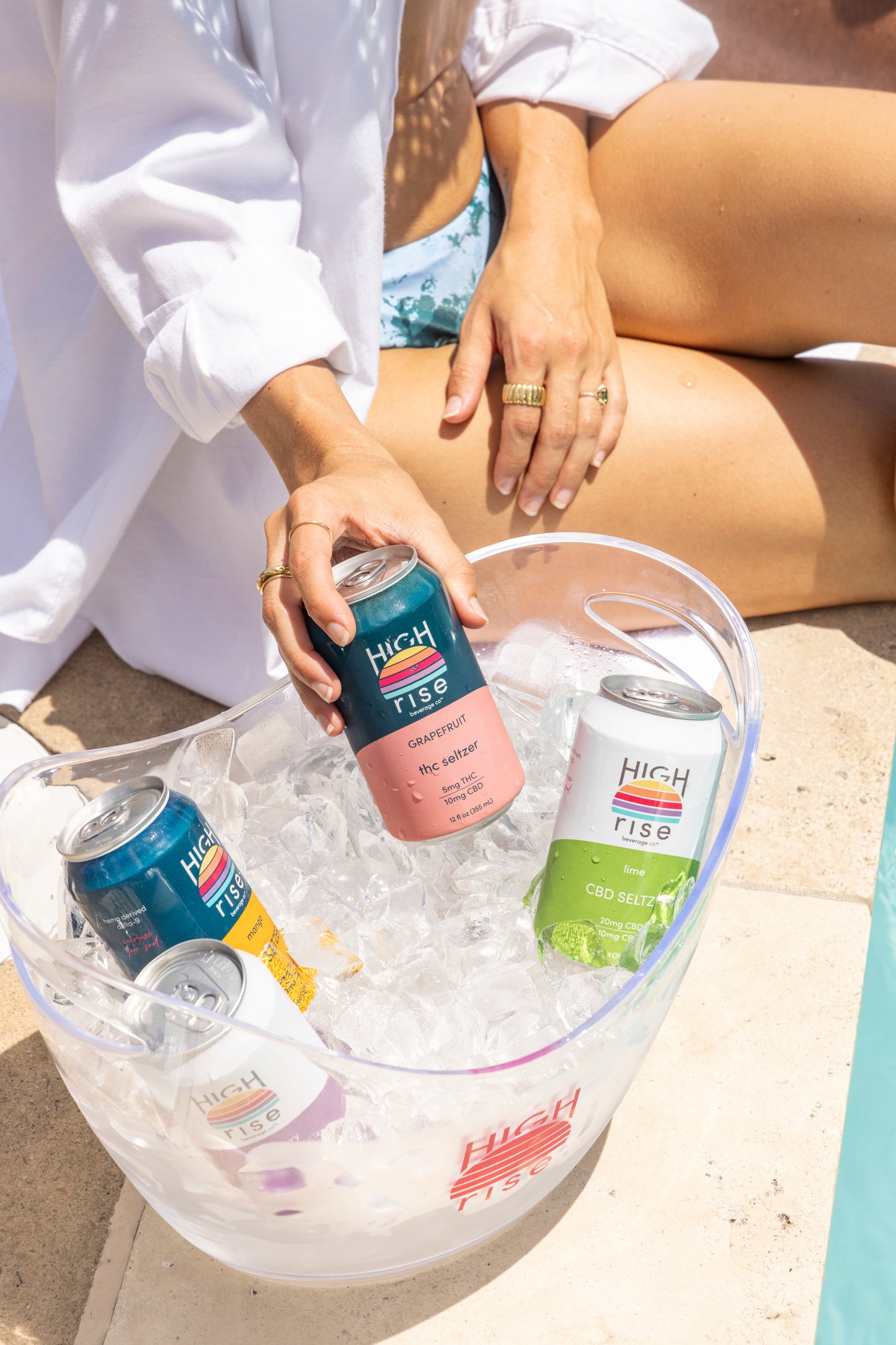 Person holding a can of High Rise Grapefruit THC Seltzer in an ice-filled container with other cans.