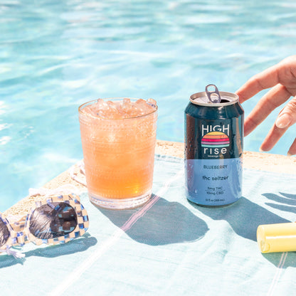 Canned drink with a glass of juice and sunglasses by a poolside