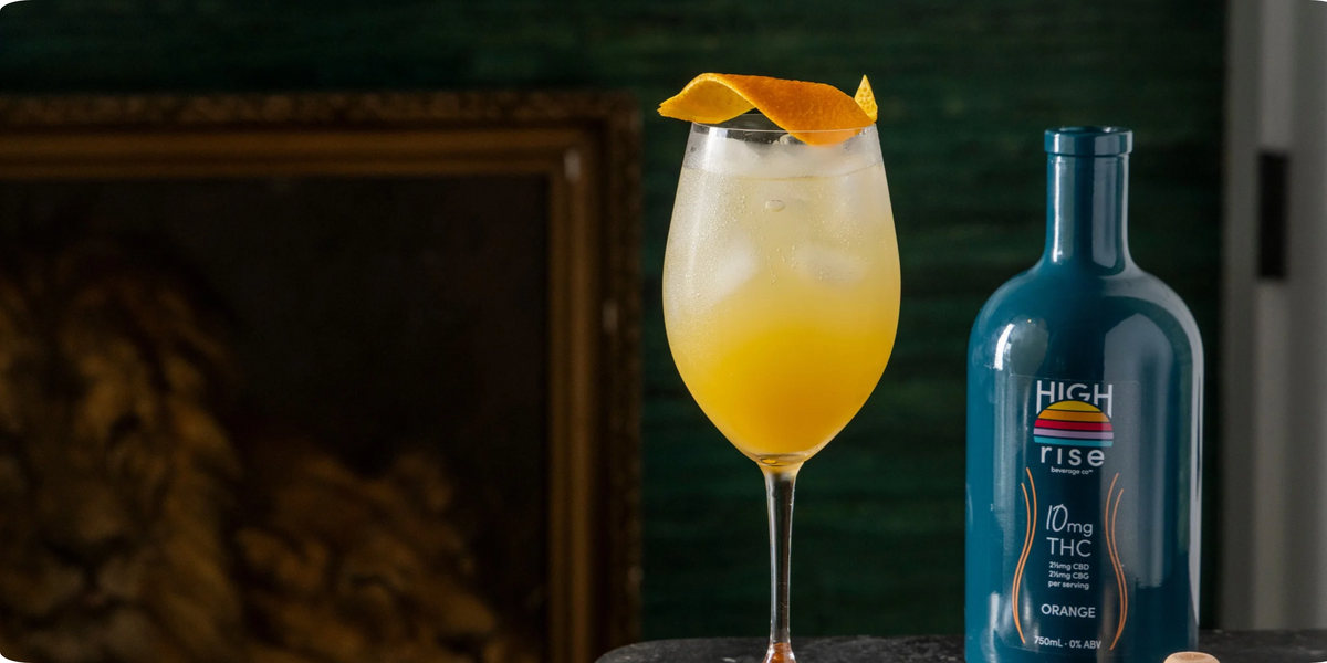 High Rise Orange THC infusion mocktail made at home with fresh orange peel on top of wine glass.