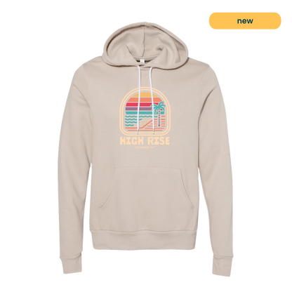 Cream hoodie with a colorful graphic and 'High Rise' text. Graphic is a sunrise on a beachfront with a palm tree, style of graphic is retro.