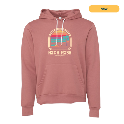 Mauve hoodie with a colorful graphic and 'High Rise' text. Graphic is a sunrise on a beachfront with a palm tree, style of graphic is retro.