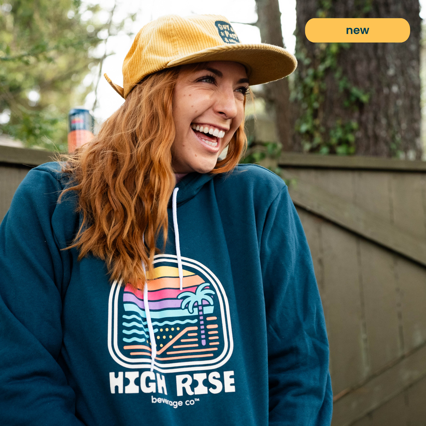 Woman smiling in navy retro High Rise hoodie, with hands in kangaroo pockets