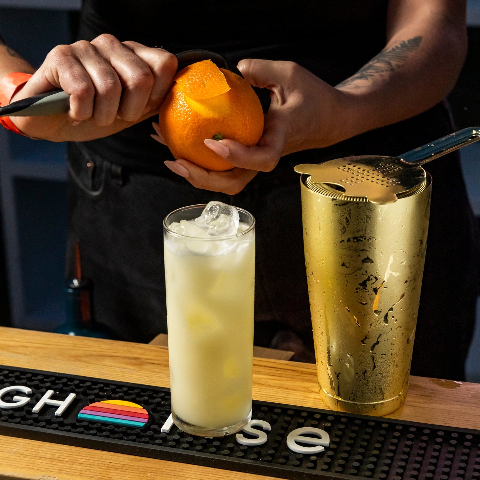Bartender preparing an orange mocktail made with high rise Orange THC infusion and peeling a fresh orange