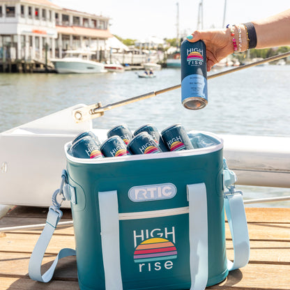 Cooler bag with High Rise 10mg THC drinks on a dock with a boats in the background.