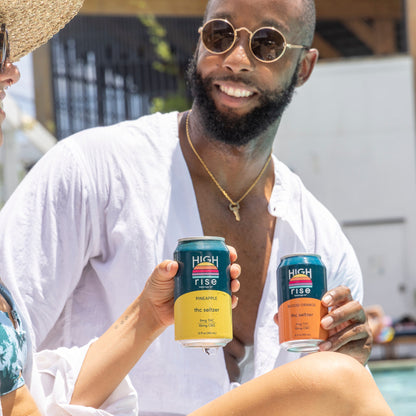 Two people sitting by a pool holding Pineapple and Blood Orange Hight Rise THC cans.